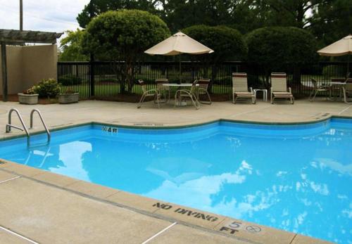 a swimming pool with a table and chairs and an umbrella at Hampton Inn New Bern in New Bern