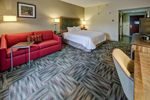 a hotel room with a bed and a red couch at Hampton Inn Newberry Opera House in Newberry