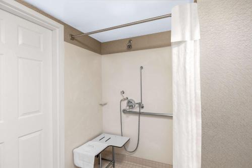 a bathroom with a shower with a bench and a shower curtain at Homewood Suites by Hilton Newark Fremont in Fremont