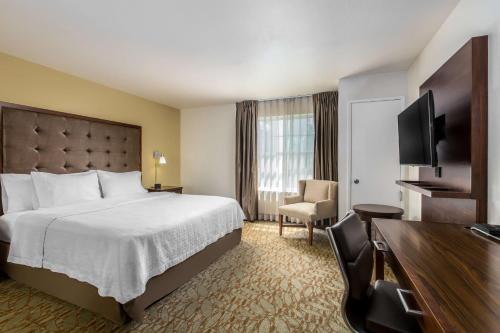 a hotel room with a bed and a flat screen tv at Homewood Suites by Hilton Newark Fremont in Fremont