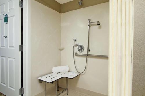 a shower stall in a bathroom with a stool at Homewood Suites by Hilton Newark Fremont in Fremont