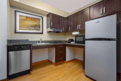 a kitchen with wooden cabinets and a white refrigerator at Homewood Suites by Hilton Newark Fremont in Fremont