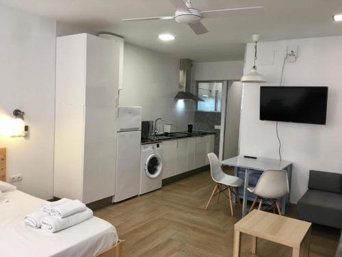 a living room with a table and a kitchen with a refrigerator at Apartamento full equip. in Bilbao