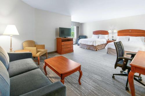 a hotel room with a bed and a couch and a tv at Hampton Inn & Suites North Conway in North Conway