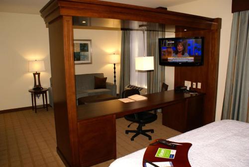 a hotel room with a desk and a tv in a mirror at Hampton Inn & Suites Center in Center