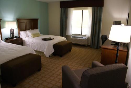 Hampton Inn & Suites Center في Center: غرفة فندقية بسريرين وكرسي