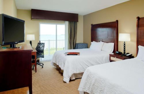 a hotel room with two beds and a flat screen tv at Hampton Inn & Suites Ocean City in Ocean City