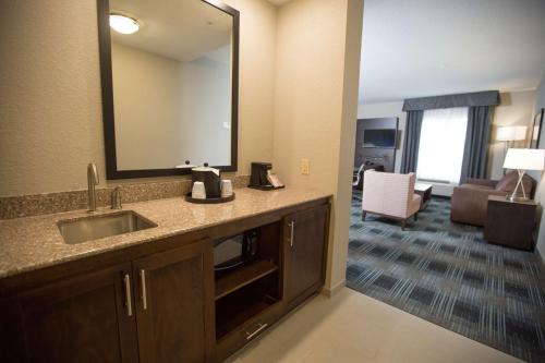 a bathroom with a sink and a mirror and a living room at Hampton Inn & Suites Oklahoma City Airport in Oklahoma City