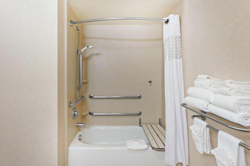 a bathroom with a tub and a shower with towels at Hampton Inn & Suites Oakland Airport-Alameda in Alameda