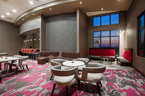 a waiting room with tables and chairs and windows at Hampton Inn & Suites Oakland Airport-Alameda in Alameda