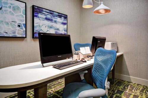 an office with a desk with a computer and blue chairs at Homewood Suites by Hilton Ocala at Heath Brook in Ocala