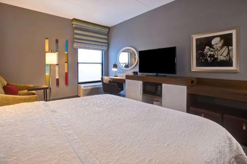 a hotel room with a bed and a flat screen tv at Hampton Inn Olive Branch in Olive Branch