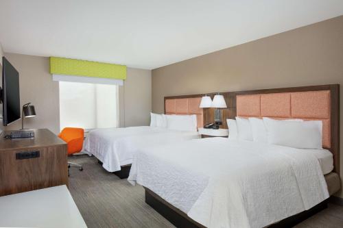 Cette chambre comprend deux lits et une télévision. dans l'établissement Newly Renovated Hampton Inn Omaha West Lakeside, à Omaha