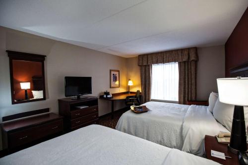 a hotel room with two beds and a television at Hampton Inn by Hilton Napanee in Napanee