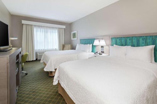 a hotel room with two beds and a flat screen tv at Hampton Inn West Palm Beach-Lake Worth-Turnpike in Lake Worth