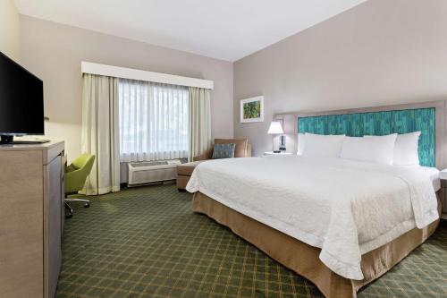 een hotelkamer met een groot bed en een televisie bij Hampton Inn West Palm Beach-Lake Worth-Turnpike in Lake Worth