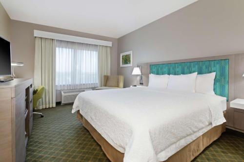 a hotel room with a large bed and a television at Hampton Inn West Palm Beach-Lake Worth-Turnpike in Lake Worth