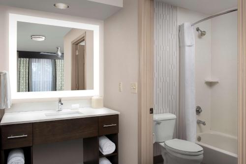 a bathroom with a sink and a toilet and a mirror at Homewood Suites Hillsboro Beaverton in Beaverton