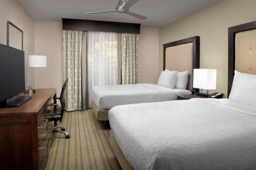 a hotel room with two beds and a flat screen tv at Homewood Suites Hillsboro Beaverton in Beaverton