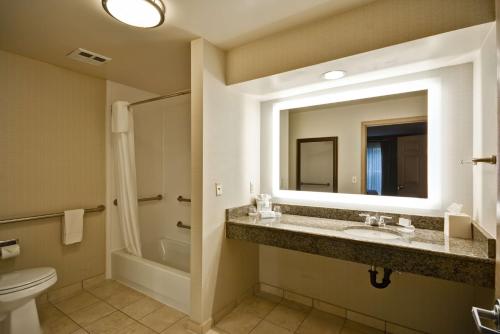 a bathroom with a sink and a toilet and a mirror at Homewood Suites Hillsboro Beaverton in Beaverton