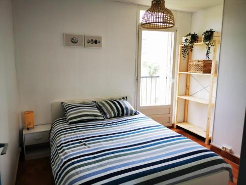 Schlafzimmer mit einem Bett mit blauen und weißen Streifen in der Unterkunft Charmant T2 climatisée au coeur du village in Saint-Mandrier-sur-Mer