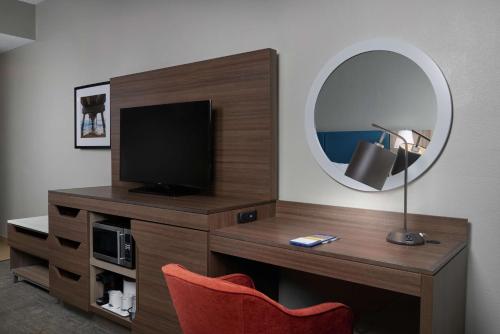 a room with a desk with a television and a mirror at Hampton Inn Juno Beach in Juno Beach