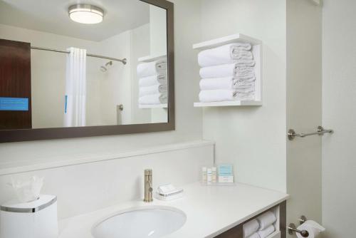 a bathroom with a sink and a mirror and towels at Hampton Inn Juno Beach in Juno Beach