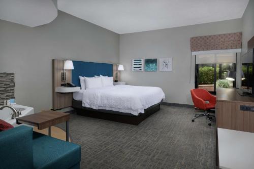 a hotel room with a bed and a living room at Hampton Inn Juno Beach in Juno Beach