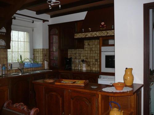 une cuisine avec des armoires en bois et un comptoir dans l'établissement Kerbarbo, à Plouagat