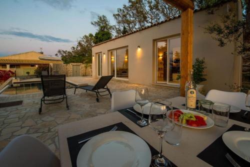 a table with a plate of food and wine glasses at Terra villa by PaxosRetreats in Lákka