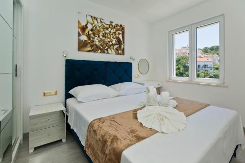 a white bedroom with two beds and a window at Luxury Apartment Veronika in Hvar