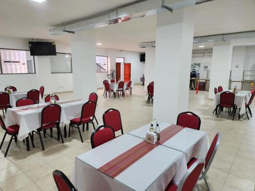 un comedor con mesas blancas y sillas rojas en Illary Hoteles, en Pozo Almonte