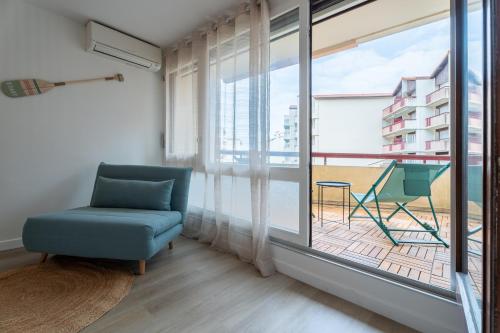a room with a chair and a large window at Le Sable Doré - Piscine et parking in Capbreton