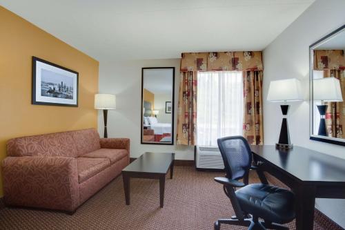 ein Wohnzimmer mit einem Sofa und einem Schreibtisch in einem Hotelzimmer in der Unterkunft Hampton Inn Pittsburgh/West Mifflin in West Mifflin