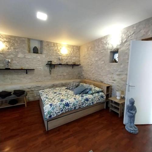 a bedroom with a bed and a stone wall at Gite dans une ancienne corps de ferme D in Provins