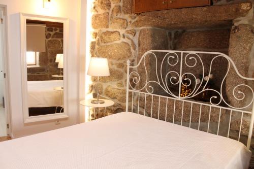 een slaapkamer met een bed en een stenen muur bij Quinta da Mó in Terras de Bouro
