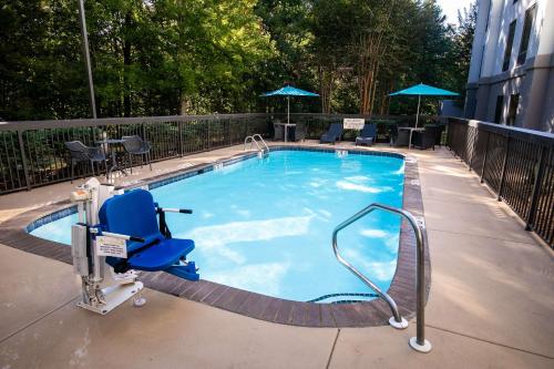 Counce的住宿－皮克威克達姆漢普頓酒店- 位於夏伊洛瀑布，大楼前带蓝色椅子的大型游泳池