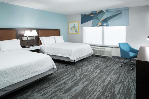 a hotel room with two beds and a chair at Hampton Inn & Suites Panama City Beach-Pier Park Area in Panama City Beach