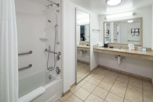 a bathroom with a shower and a tub and a sink at Hampton Inn & Suites Panama City Beach-Pier Park Area in Panama City Beach