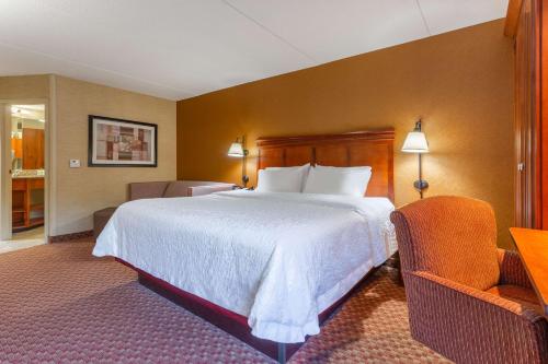 a hotel room with a large bed and two chairs at Hampton Inn East Peoria in Peoria