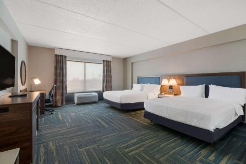 a hotel room with two beds and a flat screen tv at Hampton Inn & Suites Plattsburgh in Plattsburgh