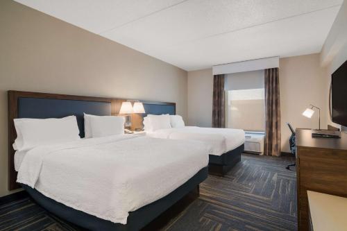 a hotel room with two beds and a flat screen tv at Hampton Inn & Suites Plattsburgh in Plattsburgh
