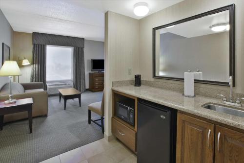 a hotel room with a sink and a living room at Hampton Inn & Suites Plattsburgh in Plattsburgh