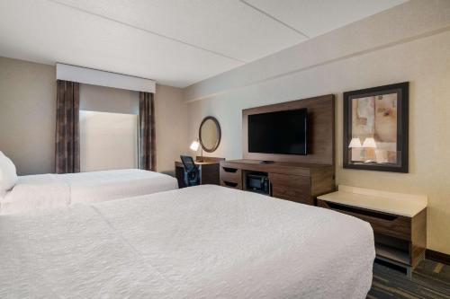 a hotel room with two beds and a flat screen tv at Hampton Inn & Suites Plattsburgh in Plattsburgh
