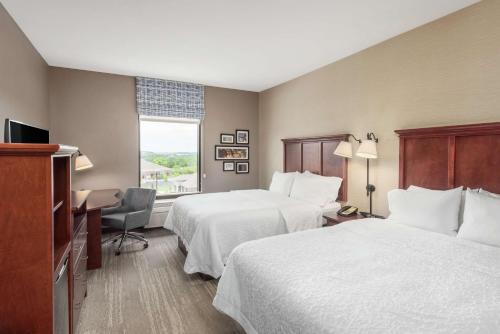 ein Hotelzimmer mit 2 Betten, einem Schreibtisch und einem Fenster in der Unterkunft Hampton Inn Branson - Branson Hills in Branson