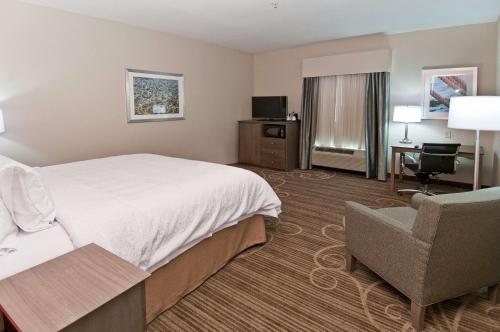 a hotel room with a bed and a chair at Hampton Inn & Suites Pensacola/I-10 Pine Forest Road in Pensacola
