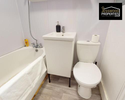 a white bathroom with a toilet and a bath tub at Stylish 3 Bedroom House by Jesswood Properties Short Lets near M1 Luton Airport For Contractors & Business in Luton