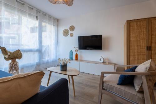 a living room with a couch and a tv at Le Sable Doré - Piscine et parking in Capbreton