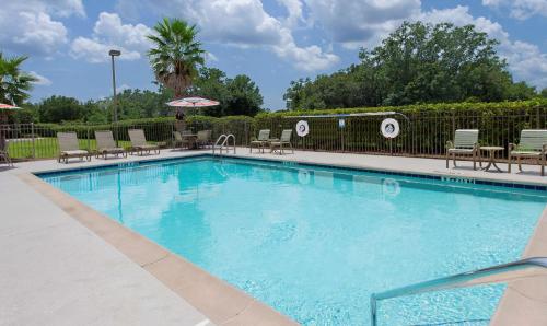 Hampton Inn & Suites Pensacola I-10 N at University Town Plaza في بينساكولا: مسبح ازرق كبير مع كراسي ومظلات