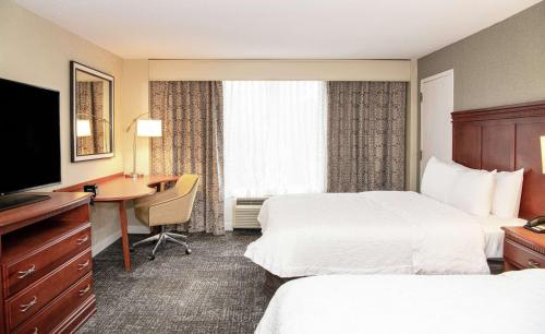 a hotel room with two beds and a desk and a television at Hampton Inn Parsippany in Parsippany